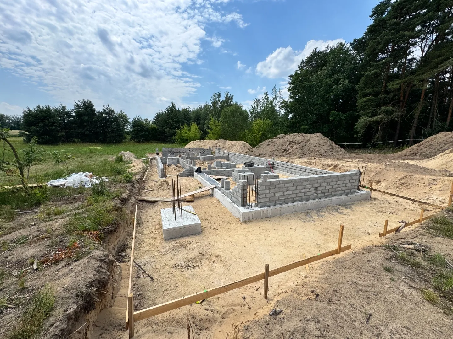 Fundamenty domu jednorodzinnego z bloczków betonowych na pełnym kadrze — budowa pod nadzorem kierownika, błękitne niebo nad polskim Mazowszem